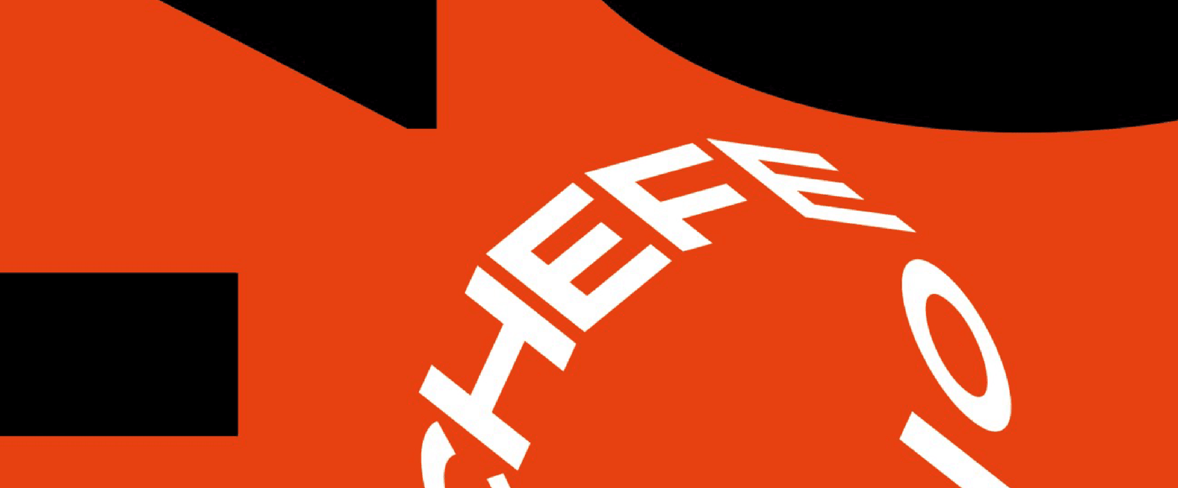 The seal: the circular CHEFE DO ANO lock-up, its letters set around a ring and reversed in white out of the brand orange, cropped by the edge of the frame.