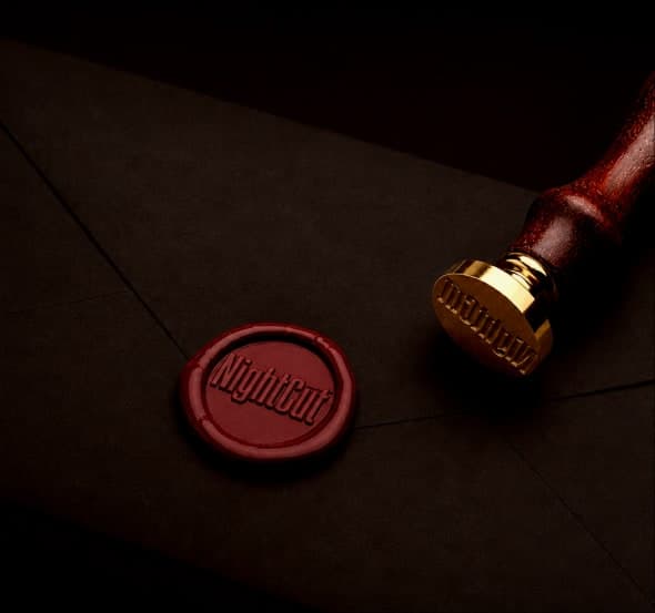 A red wax seal stamped with the mark, pressed on a dark envelope with the brass seal still resting beside it.